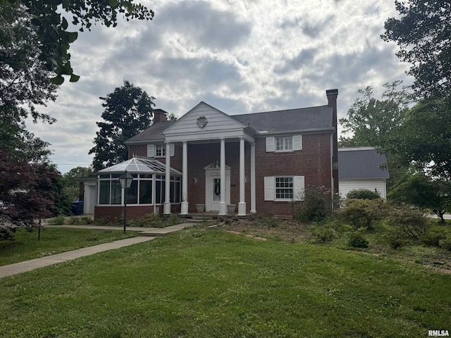 215 3rd St, Carmi, IL 62821 - neoclassical / greek revival house featuring a chimney, brick siding, a front lawn, a garage, and a sunroom