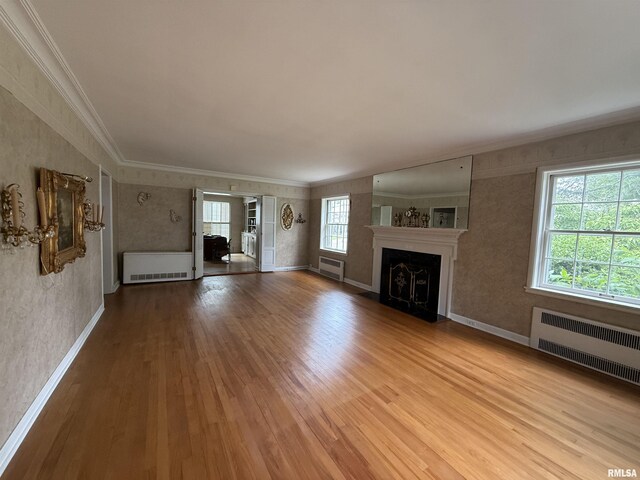 215 3rd St, Carmi, IL 62821 - unfurnished living room featuring radiator heating unit, crown molding, wood finished floors, a fireplace with flush hearth, and baseboards