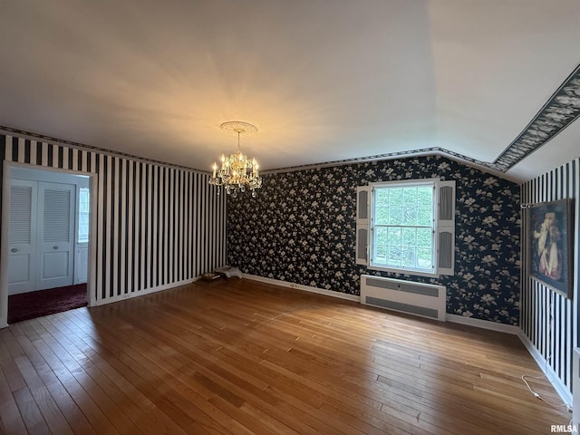 215 3rd St, Carmi, IL 62821 - spare room featuring wallpapered walls, a chandelier, wood-type flooring, vaulted ceiling, and radiator
