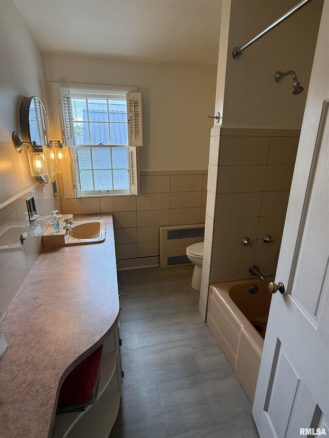 215 3rd St, Carmi, IL 62821 - bathroom featuring radiator, tile walls, toilet, vanity, and wainscoting