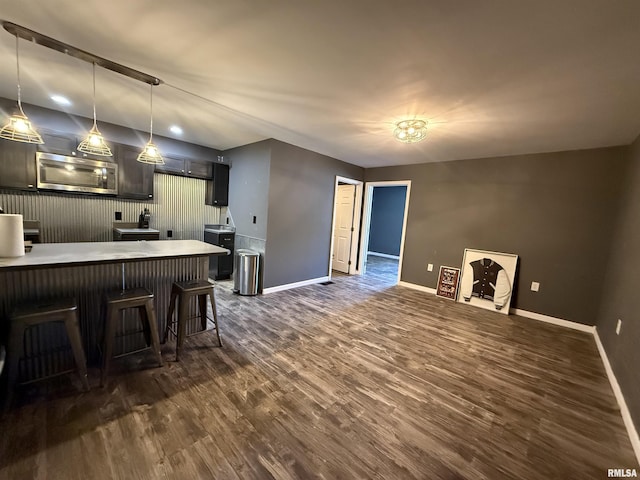 215 3rd St, Carmi, IL 62821 - kitchen featuring stainless steel microwave, baseboards, dark wood-style flooring, a kitchen breakfast bar, and pendant lighting