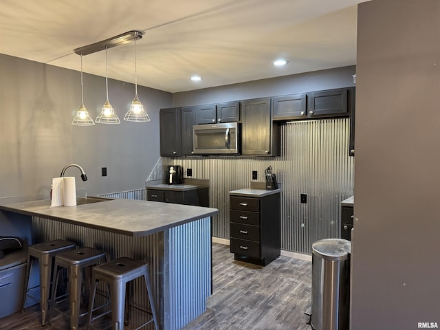 215 3rd St, Carmi, IL 62821 - kitchen featuring stainless steel microwave, dark wood-type flooring, a breakfast bar area, pendant lighting, and a sink