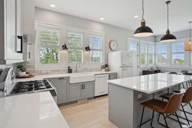 4691 Hidden Lake Ct, Bettendorf, IA 52722 - kitchen featuring white appliances, decorative backsplash, recessed lighting, light wood-style flooring, and a breakfast bar