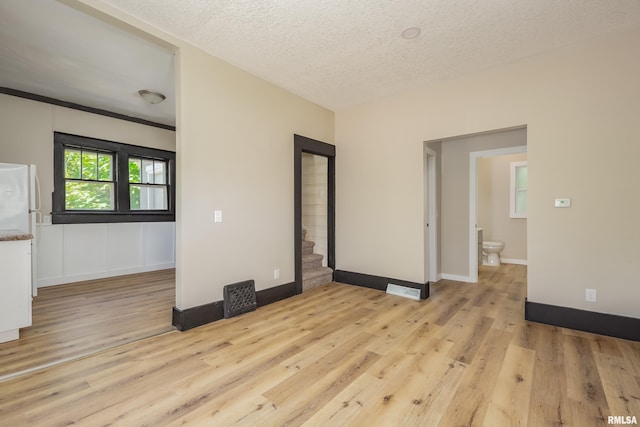 1522 Bridge Ave, Davenport, IA 52803 - spare room featuring light wood-style flooring, a textured ceiling, baseboards, and stairs