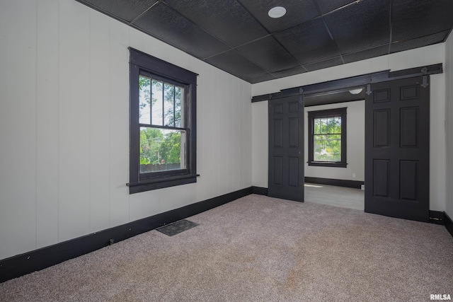 1522 Bridge Ave, Davenport, IA 52803 - carpeted empty room featuring plenty of natural light, a barn door, and baseboards
