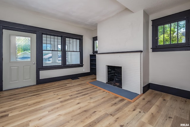 1522 Bridge Ave, Davenport, IA 52803 - unfurnished living room with wood finished floors, a brick fireplace, and baseboards
