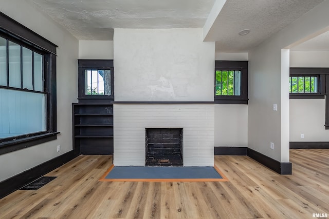 1522 Bridge Ave, Davenport, IA 52803 - unfurnished living room with wood finished floors, baseboards, a textured ceiling, and a brick fireplace