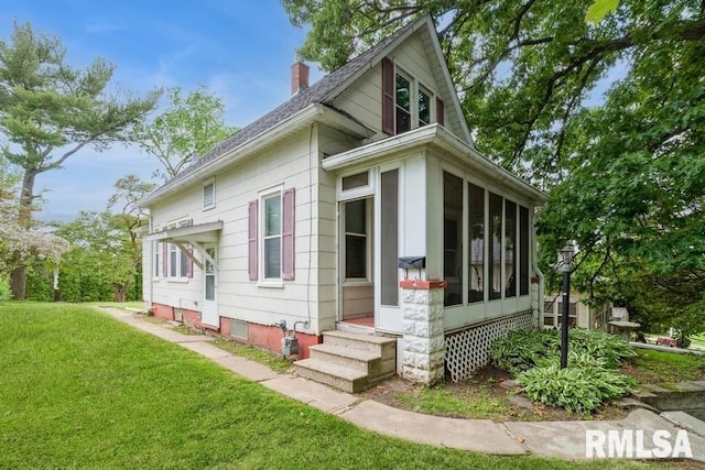 2308 18th Ave, Moline, IL 61265 - view of side of home featuring a chimney, a lawn, and a sunroom