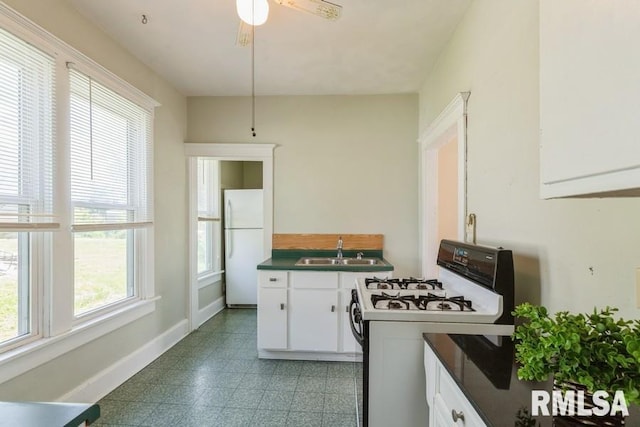 2308 18th Ave, Moline, IL 61265 - kitchen with white appliances, a sink, dark countertops, white cabinetry, and a ceiling fan