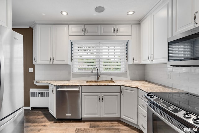 1872 19th Ave, Moline, IL 61265 - kitchen featuring appliances with stainless steel finishes, radiator heating unit, light wood-type flooring, white cabinets, and recessed lighting