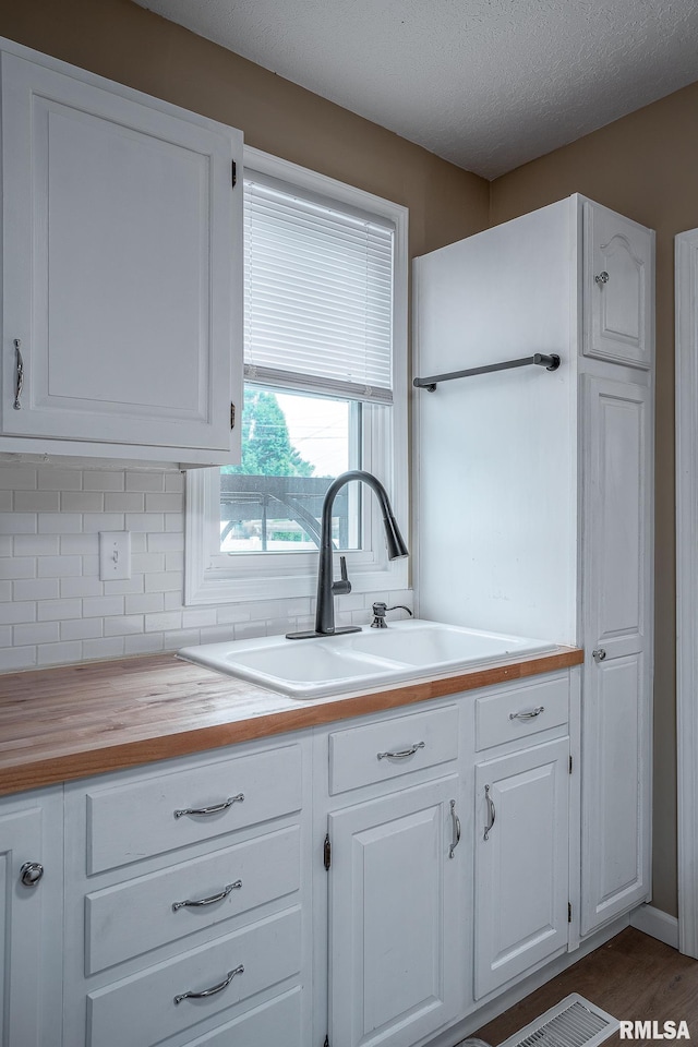 2612 7th St, Moline, IL 61265 - kitchen featuring wood counters, tasteful backsplash, a sink, white cabinets, and a textured ceiling