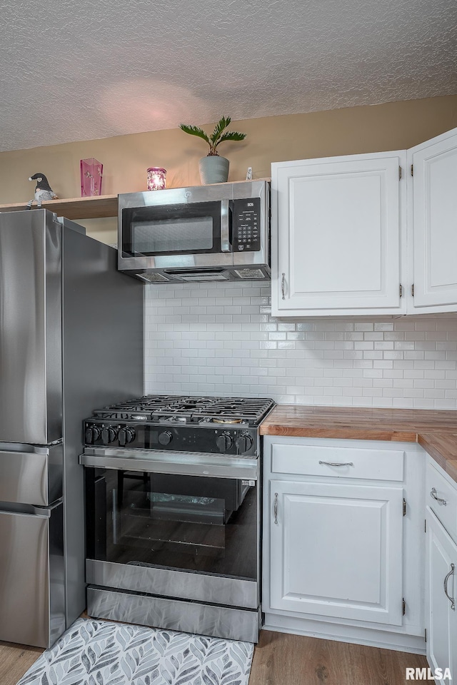 2612 7th St, Moline, IL 61265 - kitchen with stainless steel appliances, white cabinetry, wood finished floors, a textured ceiling, and backsplash
