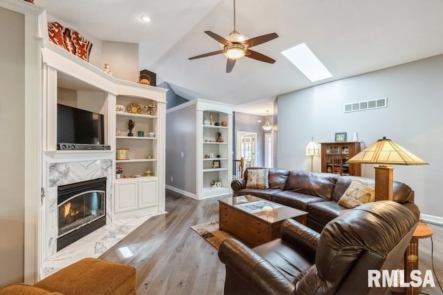 461 45th Ave, East Moline, IL 61244 - living room with a ceiling fan, lofted ceiling, a skylight, a premium fireplace, and light wood finished floors