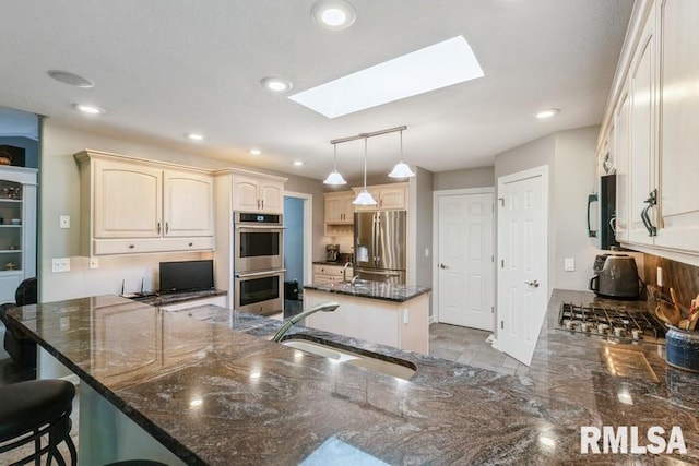 461 45th Ave, East Moline, IL 61244 - kitchen with a sink, stainless steel appliances, a skylight, a peninsula, and dark stone countertops