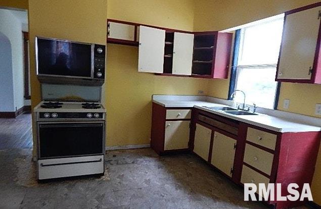 1132 W 9th St, Davenport, IA 52804 - kitchen featuring white range with gas cooktop, a sink, light countertops, and baseboards