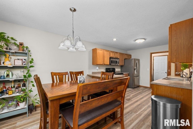 5300 Hillandale Rd, Davenport, IA 52806 - dining space featuring a chandelier, light wood-style floors, and a textured ceiling