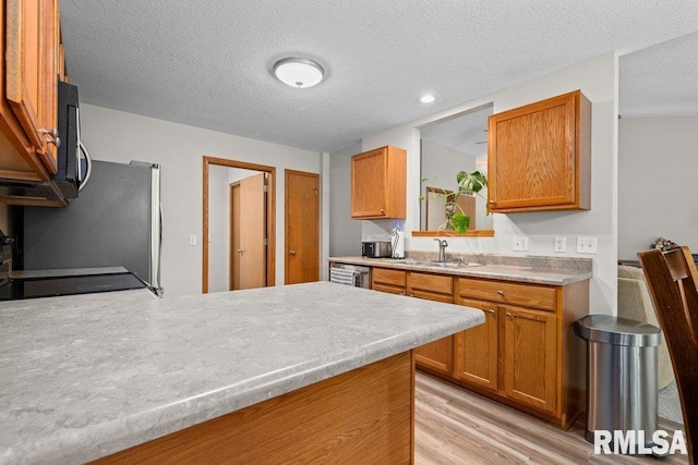 5300 Hillandale Rd, Davenport, IA 52806 - kitchen featuring light wood-style floors, light countertops, dishwashing machine, brown cabinets, and a textured ceiling