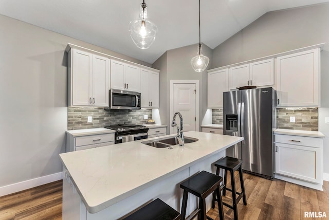 701 Sweet Wood Ln, Blue Grass, IA 52726 - kitchen featuring stainless steel appliances, tasteful backsplash, an island with sink, wood finished floors, and vaulted ceiling