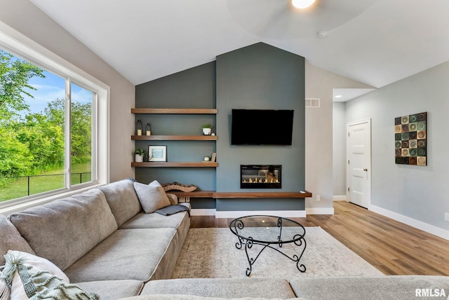701 Sweet Wood Ln, Blue Grass, IA 52726 - living area featuring wood finished floors, a glass covered fireplace, vaulted ceiling, and ceiling fan