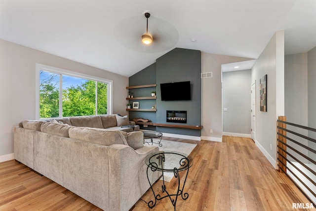 701 Sweet Wood Ln, Blue Grass, IA 52726 - living area with a ceiling fan, light wood-style flooring, vaulted ceiling, and a glass covered fireplace