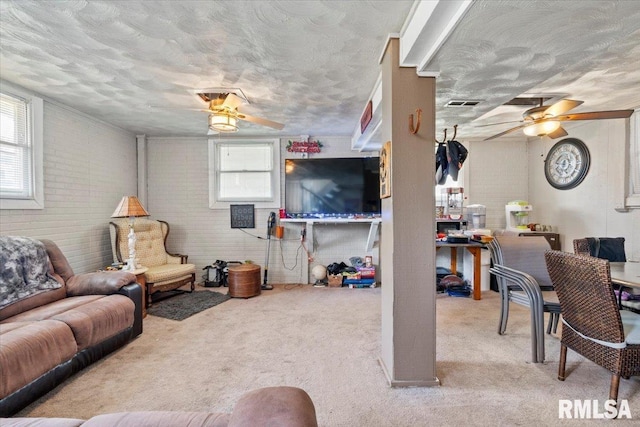 3110 N Pine St, Davenport, IA 52806 - living room featuring a ceiling fan, healthy amount of natural light, carpet flooring, brick wall, and a textured ceiling