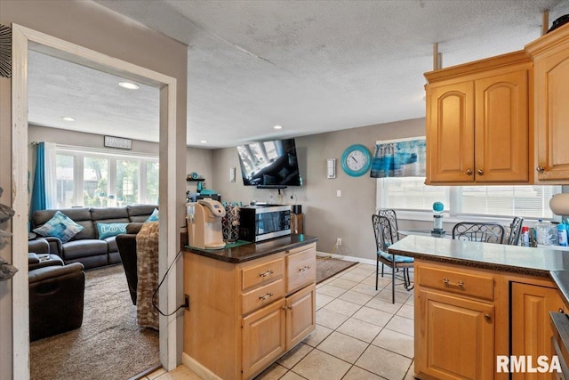 3110 N Pine St, Davenport, IA 52806 - kitchen with stainless steel microwave, dark countertops, light tile patterned floors, recessed lighting, and a textured ceiling