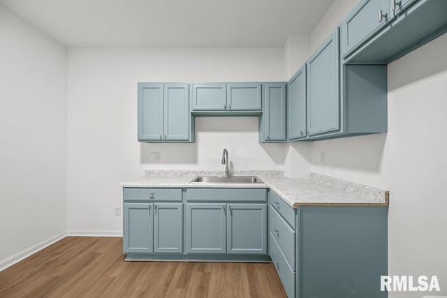 2025 W 3rd St, Davenport, IA 52802 - kitchen featuring a sink, wood finished floors, baseboards, light countertops, and blue cabinets
