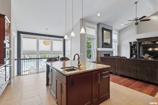 7 Redstone Ct, Le Claire, IA 52753 - kitchen featuring a sink, a ceiling fan, light tile patterned floors, high vaulted ceiling, and a stone fireplace