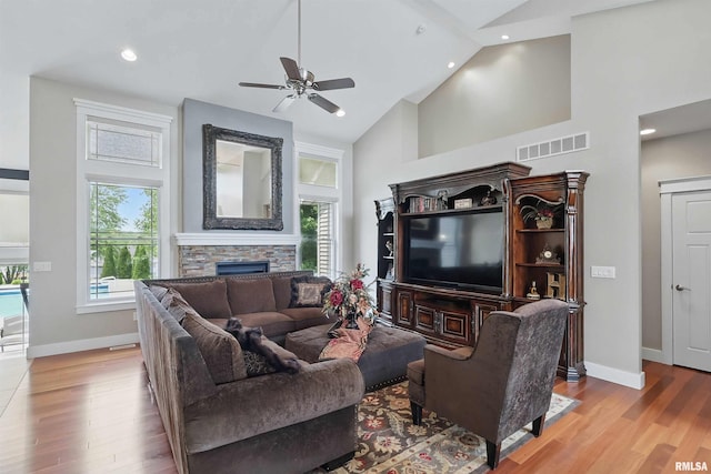 7 Redstone Ct, Le Claire, IA 52753 - living room with high vaulted ceiling, a stone fireplace, a ceiling fan, baseboards, and wood finished floors
