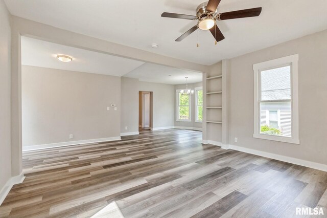 2320 E High St, Davenport, IA 52803 - unfurnished living room with wood finished floors, a chandelier, baseboards, and ceiling fan