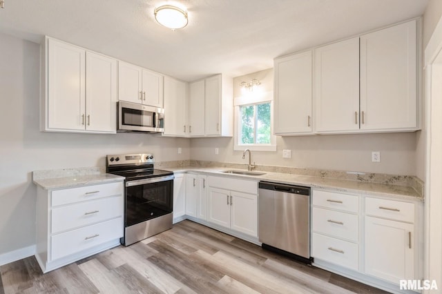 2320 E High St, Davenport, IA 52803 - kitchen with appliances with stainless steel finishes, a sink, white cabinetry, and light wood finished floors