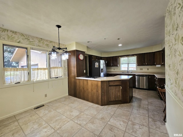 2120 Fareway Dr, Muscatine, IA 52761 - kitchen with stainless steel appliances, wallpapered walls, light countertops, a sink, and dark brown cabinets