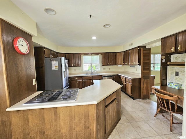 2120 Fareway Dr, Muscatine, IA 52761 - kitchen featuring stainless steel appliances, a sink, light countertops, dark brown cabinetry, and light tile patterned flooring