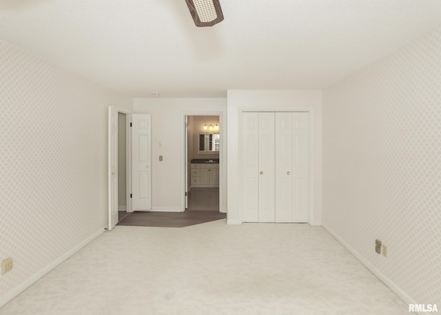 1360 Kimberly Ridge Rd Unit 313, Bettendorf, IA 52722 - unfurnished bedroom with carpet, connected bathroom, a closet, a ceiling fan, and wallpapered walls