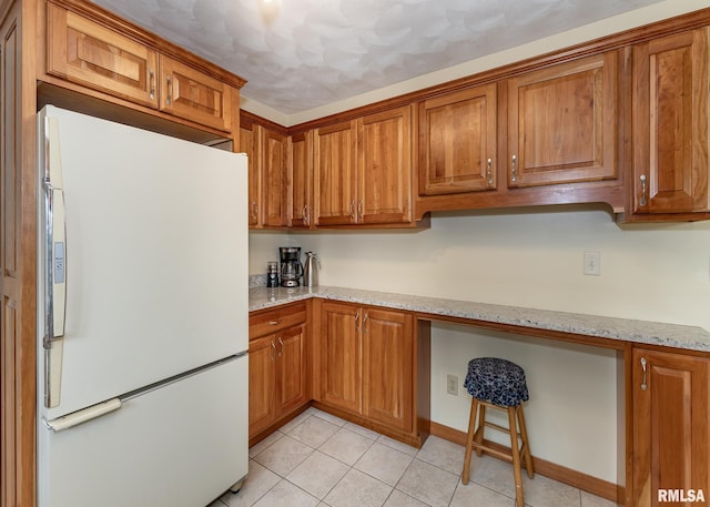 1523 7th St, Orion, IL 61273 - kitchen featuring freestanding refrigerator, brown cabinetry, and light stone counters