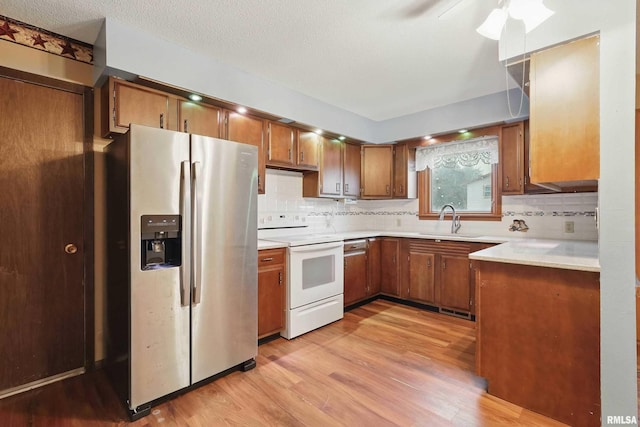 803 Locust St, Princeton, IA 52768 - kitchen with stainless steel refrigerator with ice dispenser, white electric range oven, a sink, brown cabinetry, and light wood finished floors