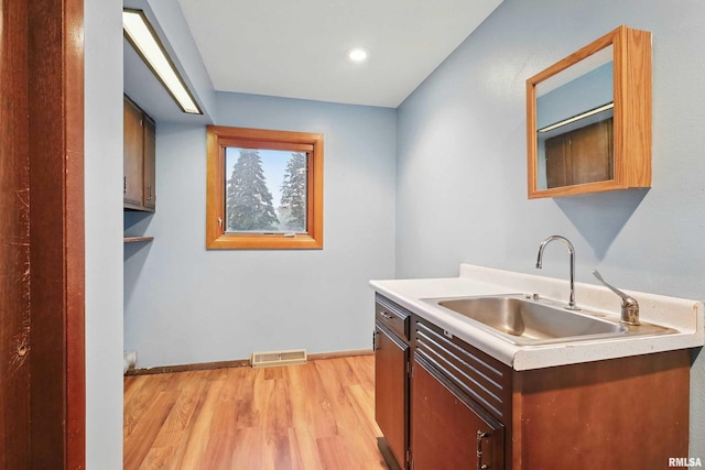 803 Locust St, Princeton, IA 52768 - kitchen featuring a sink, light countertops, light wood-style flooring, baseboards, and glass insert cabinets