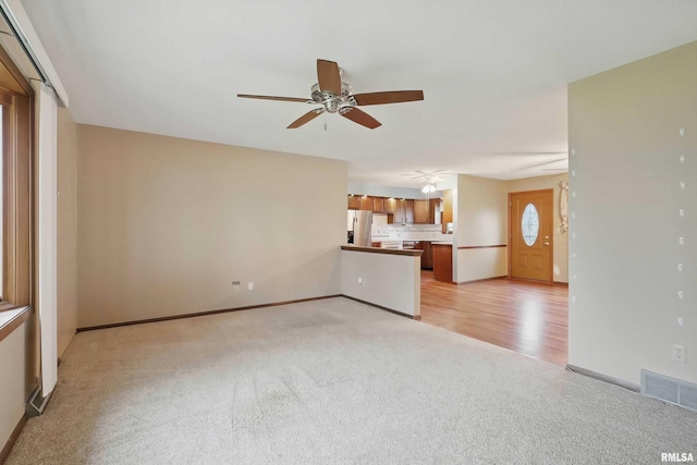 803 Locust St, Princeton, IA 52768 - unfurnished living room with light carpet, a ceiling fan, and baseboards