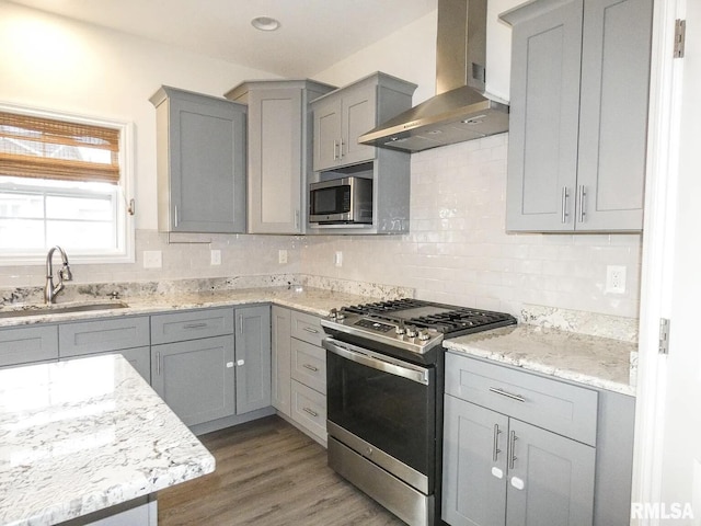 11401 N Joseph St, Dunlap, IL 61525 - kitchen featuring appliances with stainless steel finishes, wall chimney exhaust hood, gray cabinetry, decorative backsplash, and wood finished floors