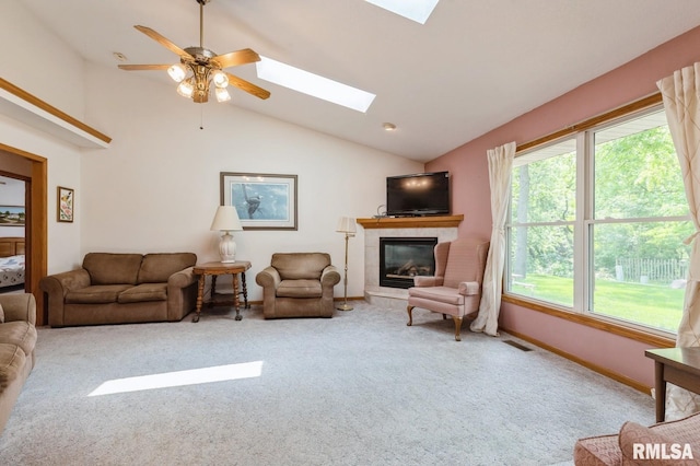 1530 N Pine St, Davenport, IA 52804 - carpeted living room with vaulted ceiling, a skylight, a tile fireplace, ceiling fan, and baseboards