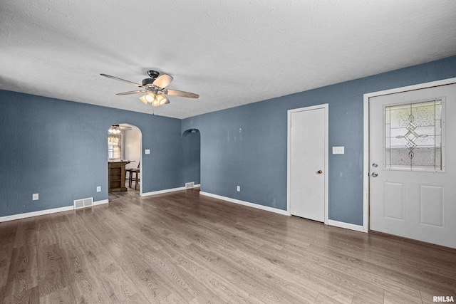 129 State St, Carbon Cliff, IL 61239 - unfurnished living room featuring arched walkways, a ceiling fan, wood finished floors, a textured ceiling, and baseboards