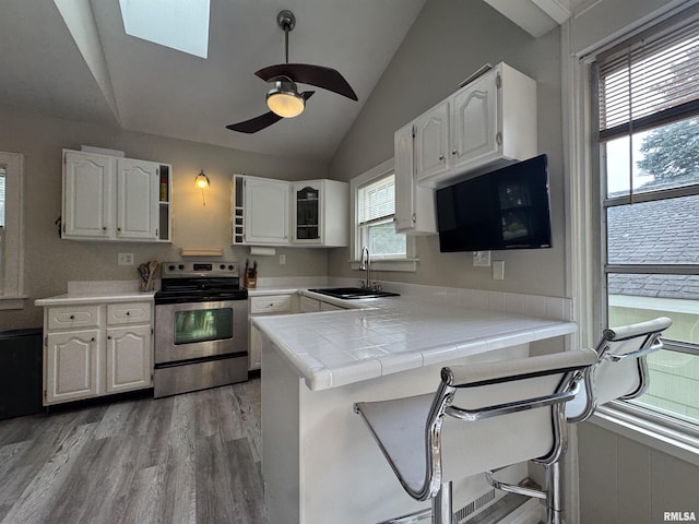 2139 10th St, East Moline, IL 61244 - kitchen featuring stainless steel electric range oven, a sink, vaulted ceiling, a peninsula, and white cabinetry