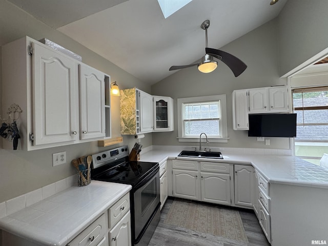 2139 10th St, East Moline, IL 61244 - kitchen featuring electric range, a sink, vaulted ceiling, white cabinets, and healthy amount of natural light