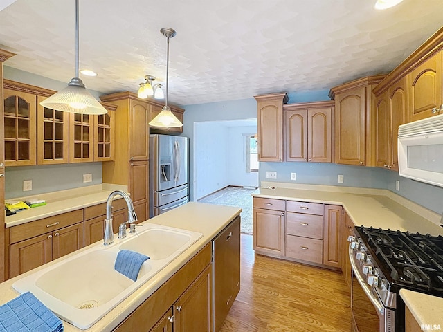 2347 W Lombard St, Davenport, IA 52804 - kitchen featuring appliances with stainless steel finishes, a sink, glass insert cabinets, hanging light fixtures, and light wood-style floors