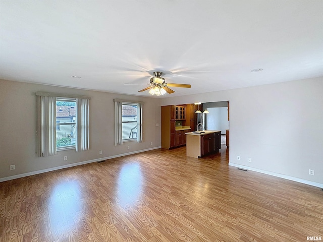 2347 W Lombard St, Davenport, IA 52804 - unfurnished living room with light wood-style floors, a ceiling fan, a sink, and baseboards