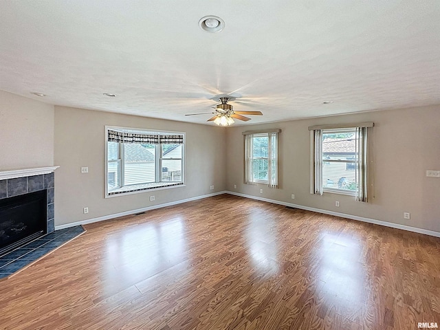 2347 W Lombard St, Davenport, IA 52804 - unfurnished living room featuring a ceiling fan, wood finished floors, a tiled fireplace, and baseboards
