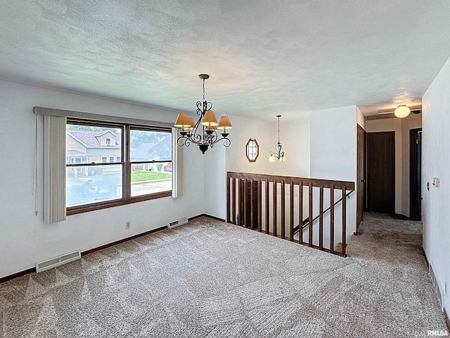 2347 W Lombard St, Davenport, IA 52804 - empty room featuring a chandelier, carpet flooring, a textured ceiling, and baseboards