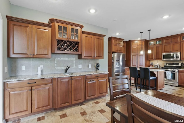 5518 Julie Ann Rd, Bettendorf, IA 52722 - kitchen featuring appliances with stainless steel finishes, brown cabinetry, decorative backsplash, a sink, and glass insert cabinets
