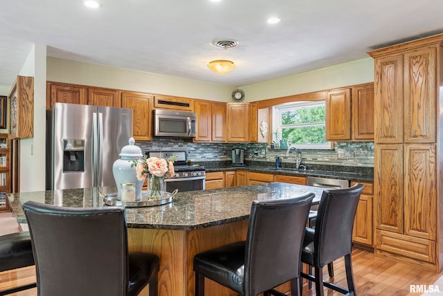 11 Shady Ln, Geneseo, IL 61254 - kitchen with appliances with stainless steel finishes, a sink, a kitchen breakfast bar, tasteful backsplash, and brown cabinets