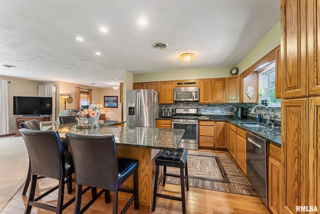 11 Shady Ln, Geneseo, IL 61254 - kitchen featuring appliances with stainless steel finishes, a sink, brown cabinetry, a kitchen bar, and a kitchen island